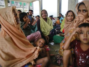Members of Myanmar's Muslim Rohingya minority who were detained by Bangladeshi border guards while crossing the Naf River to enter Bangladesh sit at a temporary shelter at Shah Porir Deep, in Teknak, Bangladesh, Thursday, Aug. 31, 2017. Three boats carrying ethnic Rohingya fleeing violence in Myanmar have capsized in Bangladesh and 26 bodies of women and children have been recovered, officials said Thursday. Last week, a group of ethnic minority Rohingya insurgents attacked at least two dozen police posts in Myanmar's Rakhine state, triggering fighting with security forces that left more than 100 people dead and forced at least 18,000 Rohingya to flee into neighboring Bangladesh. (AP Photo/Suvra Kanti Das)
