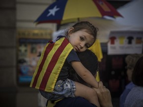 EDS NOTE : SPANISH LAW REQUIRES THAT THE FACES OF MINORS ARE MASKED IN PUBLICATIONS WITHIN SPAIN A woman carries a girl on her shoulders wearing an "estelada" or independence flag, during the Catalan National Day in Barcelona, Spain, Monday, Sept. 11, 2017. Hundred of thousands of people are expected to demonstrate in Barcelona to call for the creation of a new Mediterranean nation, as they celebrate the Catalan National Day holiday. (AP Photo/Santi Palacios)