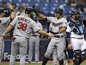 Minnesota Twins' Ehire Adrianza, second from right, celebrates with Robbie Grossman, left, and Chris Gimenez, second from left, after Adrianza hit a three-run home run off Tampa Bay Rays starting pitcher Blake Snell during the second inning of a baseball game Wednesday, Sept. 6, 2017, in St. Petersburg, Fla. Looking on is Rays catcher Jesus Sucre, right. (AP Photo/Chris O'Meara)