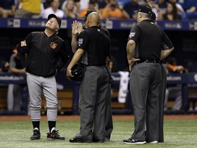 Baltimore Orioles manager Buck Showalter, left, looks up at the catwalk with the umpiring crew, including home plate umpire Vic Carapazza, center, and Bill Welke, right, after Tampa Bay Rays' Cesar Puello pop-up hit a ring over home plate and landed fair during the fourth inning of a baseball game Friday, Sept. 29, 2017, in St. Petersburg, Fla. (AP Photo/Chris O'Meara)