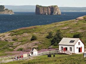 The Bonaventure Island is shown overlooking the Perce rock on July 25, 2012. The windswept archipelago of Iles-de-la-Madeleine used to spend most of every winter firmly encased in the ice of the Gulf of St. Lawrence, protected from the worst effects of winter storms. But warmer temperatures in recent years mean the surrounding waters are more often ice-free, leaving the eastern Quebec island chain at the mercy of battering waves that eat away at the coastline and put vital infrastructure at risk.