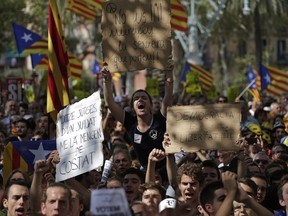 People react holding banners and waving the ''estelada'' or Catalonia independence flags during a protest in Barcelona, Spain Thursday, Sept. 21, 2017. The Catalan regional government says that a top official in the management of the region's economic affairs has been arrested as a crackdown intensifies on preparations for a secession vote that Spanish authorities have suspended. (AP Photo/Emilio Morenatti)