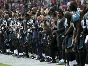 Jacksonville Jaguars owner Shahid Khan, center, joins arms with players as some kneel down during the playing of the U.S. national anthem before an NFL football game against the Baltimore Ravens at Wembley Stadium in London, Sunday Sept. 24, 2017. (AP Photo/Tim Ireland)