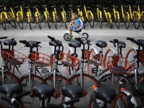 FIE - In this Aug. 31, 2017 file photo, a child rides past bicycles from bike-sharing companies parked along a sidewalk in Beijing.  A report says China's factory activity expanded in August at the fastest pace in five years, indicating a healthy outlook for the world's second-biggest economy. (AP Photo/Andy Wong, File)