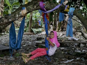 In this Tuesday, Sept. 12, 2017, photo, a Rohingya Muslim girl living in Malaysia sits on a makeshift swing outside her house in Klang, outside Kuala Lumpur, Malaysia. Recent violence in Myanmar has driven hundreds of thousands of Rohingya Muslims to seek refuge across the border in Bangladesh. There are some 56,000 Rohingya refugees registered with the U.N. refugee agency in Malaysia, with an estimated 40,000 more whose status has yet to be assessed. (AP Photo/Daniel Chan)