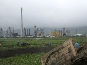 FILE - In this July 23, 2016, file photo, farmers work their fields outside the Sungri Chemical Factory, an oil refinery in the Rason Special Economic Zone near North Korea's Russian and Chinese borders. North Korea will be feeling the pain of new United Nations' sanctions targeting some of its biggest remaining foreign revenue streams, like textiles, joint ventures and remittances from its legion of workers abroad. But Pyongyang is almost certainly breathing a sigh of relieve that the Security Council eased off the biggest target of all, North Korea's access to the oil it needs to stay alive - and to fuel its million-man military. (AP Photo/Eric Talmadge, File)
