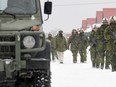 A military truck drives by soldiers in Petawawa, Ont.