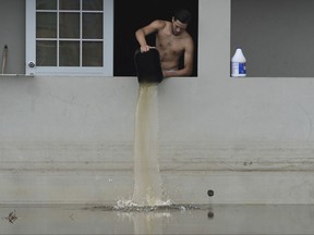 in this Wednesday, Sept. 27, 2017 photo, a resident bails water from a flooded home in the aftermath of Hurricane Maria, in Catano, Puerto Rico. A week since the passing of Maria many are still waiting for help from anyone from the federal or Puerto Rican government. But the scope of the devastation is so broad, and the relief effort so concentrated in San Juan, that many people from outside the capital say they have received little to no help. (AP Photo/Carlos Giusti)