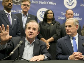 Gov. Greg Abbott, right, listens as Texas A&M University System Chancellor John Sharp, head of the Governor's Commission to Rebuild Texas, speaks about Hurricane Harvey recovery efforts at a news conference at the Texas - FEMA Joint Field Office in Austin on Tuesday, Sept. 26, 2017. (Jay Janner/Austin American-Statesman via AP)