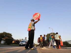 Crossing guard Frank Dewalt helps students and parents cross the street in front of Codwell Elementary School Monday, Sept. 11, 2017, in Houston.  Students in Houston are finally starting their new school year following a two-week delay because of damage from Harvey. (AP Photo/David J. Phillip)