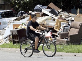 A boy rides past of debris from flooded homes in the aftermath of Hurricane Harvey Wednesday, Sept. 6, 2017, in Houston. (AP Photo/David J. Phillip)