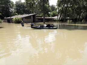 Gaston Kirby, right, and Juan Minutella leave Kirby's flooded home in the aftermath of Hurricane Harvey, Monday, Sept. 4, 2017, near the Addicks and Barker Reservoirs, in Houston. (AP Photo/David J. Phillip)