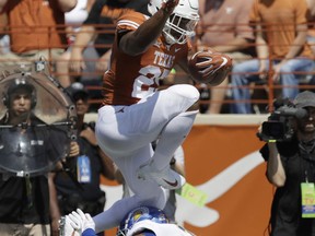 Texas running back Chris Warren III (25) leaps over San Jose State safety Maurice McKnight (10) during the first half of an NCAA college football game, Saturday, Sept. 9, 2017, in Austin, Texas. (AP Photo/Eric Gay)