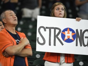 A fan holds a sign during the national anthem before the first game of a baseball doubleheader against the New York Mets, Saturday, Sept. 2, 2017, in Houston. (AP Photo/Eric Christian Smith)