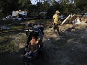 Melisa Vasquez cries in a stroller as her father Ervin Vasquez passes while the family digs out from the destruction left when floodwaters from Harvey swept through their mobile homes Monday, Sept. 4, 2017, in Crosby, Texas. Thousands of people have been displaced by torrential rains and catastrophic flooding since Harvey slammed into Southeast Texas last week. (AP Photo/Gregory Bull)