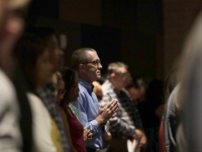 A man prays as he attends services for parishioners from flood-damaged St Ignatius Loyola Catholic Community Church in the auditorium of Klein High School Sunday, Sept. 3, 2017, in Klein, Texas. As clean up and repairs continue at the church just outside of Houston, parishioners turned this high school auditorium into their sanctuary on a Sunday that was declared National Day of Prayer for Harvey victims by President Donald Trump. (AP Photo/Gregory Bull)