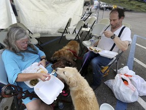 Evacuees Donna Herzog and her husband Richard Herzog, with their five dogs, eat food served by volunteers, in the aftermath of Tropical Storm Harvey, in a staging area as they wait for buses to go to evacuation shelters in Vidor, Texas, Friday, Sept. 1, 2017. (AP Photo/Gerald Herbert)