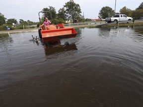 Tammy Johnston drives a tractor into floodwaters to try to retrieve some belongs for her neighbor, in the aftermath of Tropical Storm Harvey in Orange, Texas, Sunday, Sept. 3, 2017. (AP Photo/Gerald Herbert)