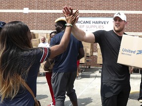 FILE - In this Sept. 3, 2017, file photo, Anna Ucheomumu, left, high fives Houston Texans defensive end J.J. Watt after loading a car with relief supplies to people impacted by Hurricane Harvey, in Houston. J.J. Watt is being honored by the NFL Players Association after raising more than $29 million for Hurricane Harvey relief efforts. Watt was named the NFLPA's Community MVP on Friday, Sept. 8, 2017,  for his work in the days since the hurricane and flooding devastated Houston and much of southeast Texas. (Brett Coomer/Houston Chronicle via AP, Pool, File)