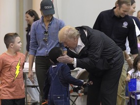 President Donald Trump and Melania Trump meet people impacted by Hurricane Harvey during a visit to the NRG Center in Houston, Saturday, Sept. 2, 2017. Trump cupped a boy's face in his hands and then gave him a high-five. It was his second trip to Texas in a week, and this time his first order of business was to meet with those affected by the record-setting rainfall and flooding. He's also set to survey some of the damage and head to Lake Charles, Louisiana, another hard-hit area. (AP Photo/Susan Walsh)