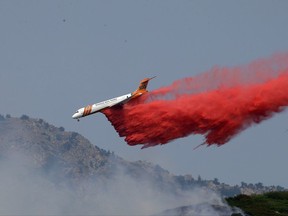 A heavy tanker drops retardant on a wildfire in Weber Canyon, Tuesday, Sept. 5, 2017, near Ogden, Utah. At least one home went up in smoke and more than 1,000 people were evacuated as high winds fed the flames that started in a canyon north of Salt Lake City. (AP Photo/Rick Bowmer)