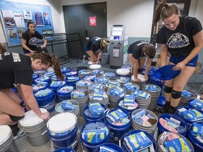 In this Sept. 25, 2017, photo, members of the community join the Eastern Mennonite University volleyball team as they pack buckets with relief kits bound for hurricane-ravaged Puerto Rico in Harrisonburg, Va.