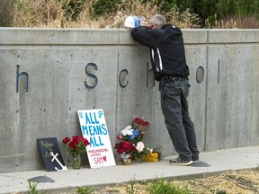 FILE - In this Sept. 14, 2017 file photo, Freeman High School assistant football coach Tim Smetana grieves after he placed roses at a memorial to the shooting victims at the school in Rockford, Wash. Students returned Monday, Sept. 18, 2017 to the school south of Spokane, Wash., for the first time since last Wednesday's shootings that left one student dead and three wounded. (Dan Pelle/The Spokesman-Review via AP, File)