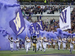 Washington cheerleaders and Harry, the Husky mascot, set off smoke effects as they lead the team out of the tunnel at Husky Stadium for Washington's home opener, an NCAA college football game against Montana, Saturday, Sept. 9, 2017, in Seattle. (AP Photo/Ted S. Warren)