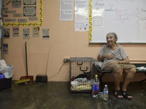 In this Sept. 19, 2017 photo, evacuee Guillermina Reyes, 90, sits with with her pet dog Blackie at the Juan Ponce de Leon Elementary School before the arrival of Hurricane Maria, in Humacao, Puerto Rico. The island took a direct hit by the category the hurricane. Authorities warned people who live in wooden or flimsy homes should find safe shelter before the storm's expected arrival on Wednesday. (AP Photo/Carlos Giusti)