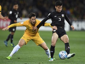 Australia's Mathew Leckie, left and Thailand's Theerathon Bunmathan struggle for the ball during their World Cup Group B qualifying soccer match in Melbourne, Australia, Tuesday, Sept. 05, 2017. (AP Photo/Andy Brownbill)