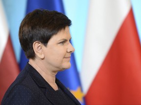 In this Sept. 5, 2017  photo Polish Prime Minister Beata Szydlo walks past EU and Polish national flag, right, in her office in Warsaw, Poland. The European Union has escalated its case against Poland over what it sees as democratic backsliding in the Central European nation as the country's ruling party is pushing to overhaul the nation's justice system in a way that gives its direct power over the courts, saying it seeks to create a more efficient justice system. (AP Photo/Alik Keplicz)