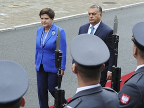 Hungarian Prime Minister Viktor Orban, right, and his Polish counterpart Beata Szydlo walk in front of the guard of honor during the welcoming ceremony in Warsaw, Poland, Friday, Sept. 22, 2017. Orban came to Poland for an official visit. (AP Photo/Alik Keplicz)