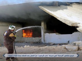 This photo released Tuesday, Sept 19, 2017 by the al-Qaida-affiliated Ibaa News Agency, that is consistent with independent AP reporting, shows a Civil Defense worker putting out a fire in Khan Sheikhoun, in the northern province of Idlib, Syria. A Syrian monitoring group says insurgents led by an al-Qaida-linked group have launched a wide offensive against pro-government troops south of their stronghold in the western province of Idlib. Arabic reads, "Al-Rahma hospital in Khan Sheikhoun is out of service after it was hit by airstrikes." (Ibaa News Agency, via AP)