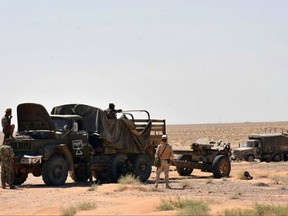 This photo released on Sunday, Sept. 3, 2017 by the Syrian official news agency SANA, shows Syrian troops and pro-government gunmen standing near military vehicles in the eastern city of Deir el-Zour, Syria. Syrian government forces and their allies are on the verge of breaking a nearly three-year siege imposed by the Islamic State group on parts of the eastern city of Deir el-Zour, advancing to within few kilometers from besieged areas, opposition activists and state media said Monday Sept. 4, 2017. (SANA via AP)
