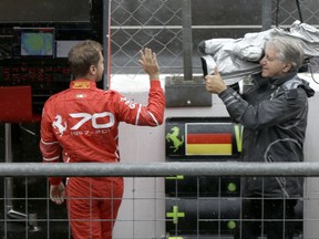 Ferrari driver Sebastian Vettel of Germany waves to a cameraman outside the team box ahead of a qualifying session for Sunday's Italian Formula One Grand Prix, at the Monza racetrack, Italy, Saturday, Sept. 2, 2017. (AP Photo/Luca Bruno)