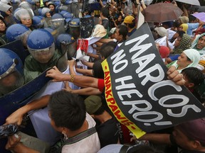 Protesters clash with police as the former try to force their way closer to the gates of the Heroes Cemetery to protest a mass and ongoing celebration for the late dictator Ferdinand Marcos on his 100th birthday Monday, Sept. 11, 2017 in suburban Taguig city east of Manila, Philippines. The protesters also scored President Rodrigo Duterte for allowing the hero's burial of Marcos at the national cemetery and declaring a non-working holiday at Marcos' home province of Ilocos Norte in northern Philippines. (AP Photo/Bullit Marquez)