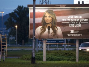 A worker carrying a ladder walks past a billboard depicting the first lady Melania Trump and advertising a language school displayed in Zagreb, Croatia, Friday, Sept. 15, 2017. (AP Photo/Darko Bandic)