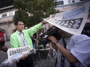 A man distributes an extra edition of a newspaper reporting about North Korea's missile launch, at Shimbashi Station in Tokyo, Friday, Sept. 15, 2017. South Korea's military said North Korea fired an unidentified missile Friday from its capital Pyongyang that flew over Japan before landing in the northern Pacific Ocean. (AP Photo/Eugene Hoshiko)
