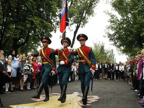 Schoolchildren watch as servicemen carry a flag of the Russia-backed self-proclaimed separatist Donetsk republic, at a ceremony on the first day of school in Donetsk, Ukraine, Friday, Sept. 1, 2017. Ukrainian government and pro-Russia separatists in eastern Ukraine have agreed to a cease-fire last month to help reduce tensions as the new school year starts Sept. 1, but the deal has been repeatedly violated. (AP Photo/Alexander Ermochenko)