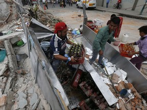 Residents remove sodas from the fridge of their taco stand after a wall collapsed on it during the earthquake in Mexico City, Friday, Sept. 8, 2017.