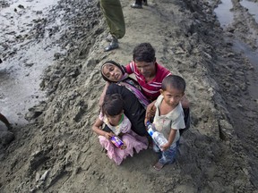 A newly arrived Rohingya Muslim Mohamed Rafiq, center, comforts his wife Noora Khatum and his children as they reach Teknaf, Bangladesh, Friday, Sept. 29, 2017. He trekked to Bangladesh as part of an exodus of a half million people from Myanmar, the largest refugee crisis to hit Asia in decades. But after climbing out of a boat on a creek on Friday, Rafiq could go no further. He collapsed onto a muddy spit of land cradling his wife in his lap, a limp figure so exhausted and so hungry she could no longer walk or even raise her wrists. (AP Photo/Gemunu Amarasinghe)