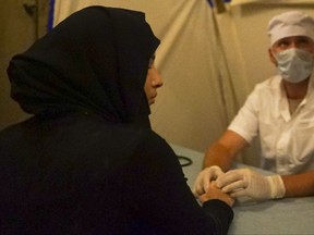 In this Wednesday, Sept. 13, 2017 photo doctor treats a local woman in a Russian military makeshift hospital at the check-point of the de-escalation zones near Homs, Syria. Hundreds of people, mostly women and elderly men, living on the both sides which recently was a frontline between Syrian government forces and the Free Syrian Army flocked to a Russian military police check-point on Wednesday to get Russian food aid. (AP Photo/Nataliya Vasilyeva)