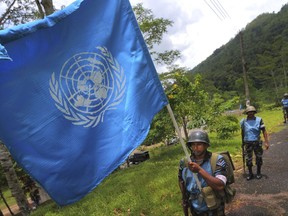 FILE - In this Sept. 13, 2016 photo, a Sri Lanka Air Force airman carries the U.N. flag during training for a road patrol at the Institute of Peace Support Operations Training in Kukuleganga, Sri Lanka. A U.N. fund to help victims of sexual abuse and exploitation by peacekeepers and U.N. staff has now grown to $1.5 million following contributions from 10 more countries including Sri Lanka, whose troops were implicated in a three-year-long child sex ring in Haiti. The U.N. Department of Field Support made the announcement Thursday, Sept. 28, 2017 in New York. (AP Photo/Eranga Jayawardena, file)