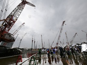 Members of the media review the construction of the new national stadium in Tokyo, Tuesday, Sept. 12, 2017. Tokyo's main Olympic stadium is starting to take shape as structures of what will become spectator stands are being installed after 10 months of underground foundation work. (AP Photo/Shizuo Kambayashi)