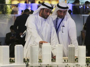 People look at an architectural model of a housing development at the Cityscape Global exhibition, Monday, Sept. 11, 2017, in Dubai, United Arab Emirates. Tens of thousands of luxury projects were on display at Dubai's premier property show on Monday, but missing from the glittering mock-ups and pipeline of housing dreams being rolled out were more affordable housing projects for the region's large and burgeoning population of young and aspiring home owners. (AP Photo/Kamran Jebreili)