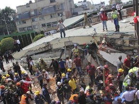 FILE- In this Sept. 19, 2017 file photo, rescue workers search for children trapped inside the collapsed Enrique Rebsamen school in Mexico City. Authorities said that the owner of the privately owned Enrique Rebsamen school built an apartment for herself on top of the collapsed wing, which local media said included a Jacuzzi, and were looking into whether the extra weight may have played a role in the collapse. (AP Photo/Carlos Cisneros, File)