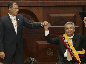 FILE - In this May 24, 2017 file photo, incoming President Lenin Moreno, right, raises his hand with outgoing President Rafael Correa, during the presidential swearing-in ceremony, in Quito, Ecuador. Moreno angrily denounced Friday, Sept. 15, 2017, what he says is the discovery in his office of a hidden video camera that allegedly could be monitored on his predecessor's cellphone. (AP Photo/Dolores Ochoa, File)