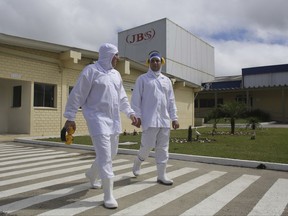 FILE - In this March 21, 2017 file photo, employees walk on the plant grounds of meatpacker JBS, in Lapa, in the Brazilian state of Parana. A Brazilian Supreme Court justice has ordered on Sunday, Sept. 10, the arrest of the former JBS chairman Joesley Batista, whose testimony implicated Brazil's President Michel Temer in corruption. (AP Photo/Eraldo Peres, File)