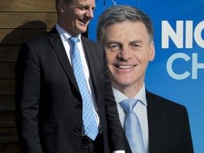 FILE - In this Aug. 24, 2017 file photo, New Zealand Prime Minister Bill English stands by billboard with his photo in Christchurch, New Zealand. Advance voting began Monday, Sept. 11, 2017 for New Zealand's general election, which could see a change of government in the South Pacific nation for the first time in nine years. (AP Photo/Mark Baker,File)