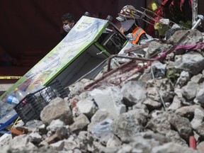 Rescues workers walk past rubble in San Gregorio Atlapulco, Mexico, Friday, Sept. 22, 2017. Mexican officials are promising to keep up the search for survivors as rescue operations stretch into a fourth day following Tuesday's major earthquake that devastated Mexico City and nearby states. (AP Photo/Moises Castillo)
